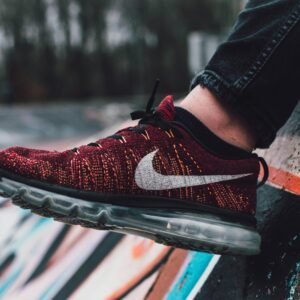 Vibrant red sneaker displayed against a dynamic graffiti wall in outdoor setting.